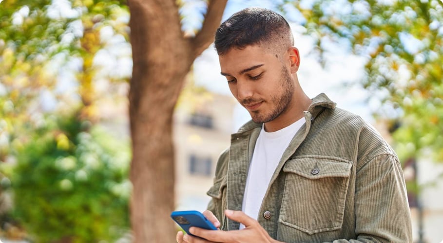 Man looking at phone with tree in back